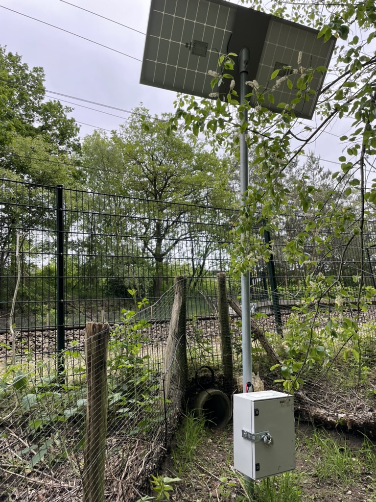 De meetopstelling bij een amfibieëntunnel, met zonnepaneel en elektronicakast.