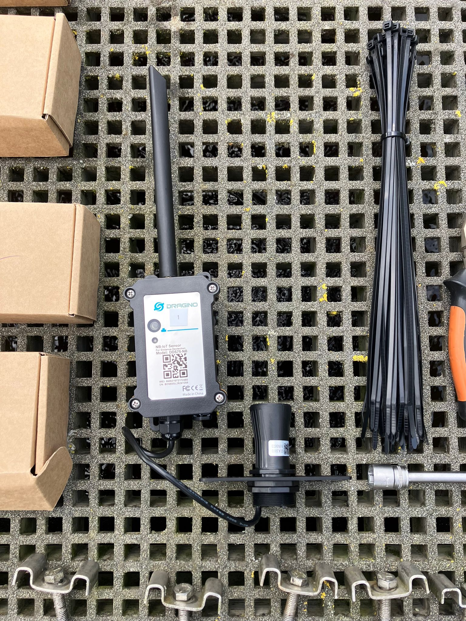 De sonische meetkop, zender en montagematerialen voor installatie.