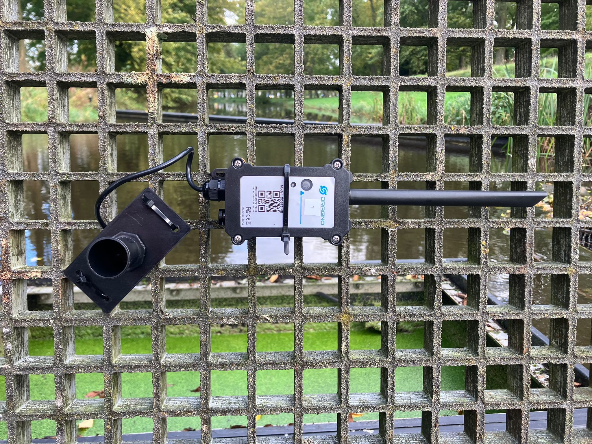 De sonische sensor met zender en antenne, bevestigd aan het rooster.